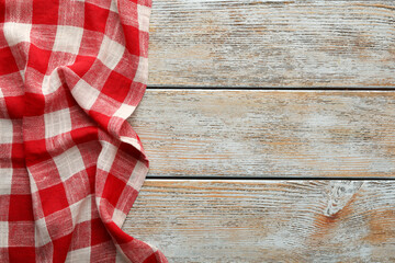 Obraz premium Red checkered picnic tablecloth on old wooden table, top view. Space for text