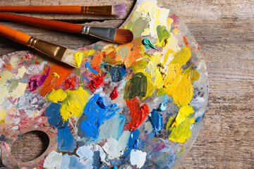 Obraz premium Artist's palette, brushes and paints on wooden table, flat lay