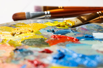 Obraz premium Artist's palette, brushes, paints on table, closeup