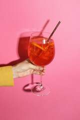 Woman with glass of refreshing cocktail on pink background, closeup