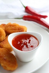 Chili sauce and chicken nuggets on white table