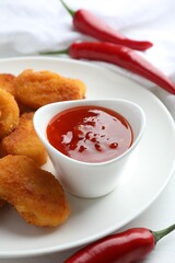 Chili sauce and chicken nuggets on white table