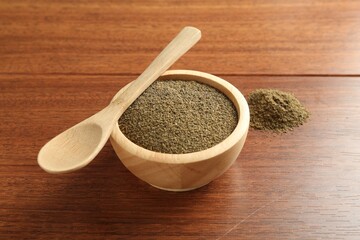 Superfood powder in bowl and spoon on wooden table, closeup