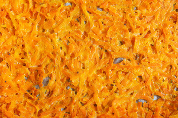 Overhead view of a close-up of grated carrot baked on a tray with parchment paper. Organic textures.