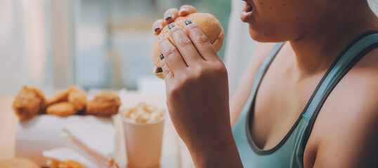 Binge eating disorder concept with woman eating fast food burger, fired chicken , donuts and desserts