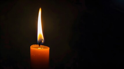 Single lit candle flame in the dark with a blurred background
