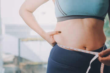 fat woman, fat belly, chubby, obese woman hand holding excessive belly fat with measure tape, woman diet lifestyle concept