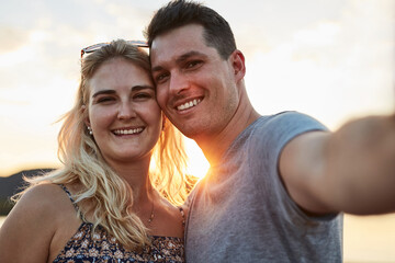 Obraz premium Couple, selfie and sunset in nature for vacation, relax and travel with love, memory and leisure in California. People, portrait and happy for holiday, relationship and adventure with smile by lake