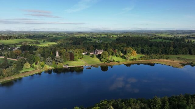 Castle Leslie, Glaslough, County Monaghan, Ireland, September 2022. Drone tracks across the forest on the north side of the lake as cloud shadows roll across the beautiful estate.