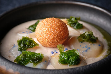 Plate of delicious cream soup with scallop decorated with lettuce