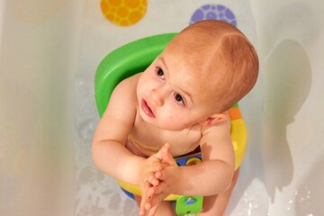 Aerial photo of a baby sitting in a colorful chair in a bathtub