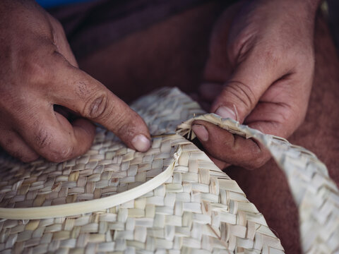 Close-up of hands skillfully weaving a palmito basket