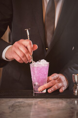 Bartender in black suit mixing cocktail at counter