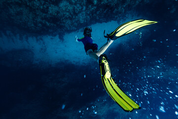From above full body of unrecognizable active teen boy wearing yellow flippers snorkeling by coral reef in deep ocean with crystal clear waters at Menorca © ADDICTIVE STOCK CORE