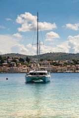 Anchored catamaran boat, anchored in the fornt of small town of Rogoznica, Croatia