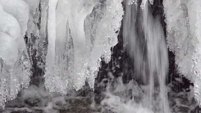 This is a close up of water flowing under a cover of ice into a stream in winter.