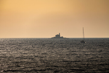 Stone lighthouse Mulo far on the horizon in front of small tourist town of Rogoznica, Croatia, on the open, Adriatic sea