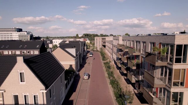 Slow aerial forward movement showing Dutch residential neighbourhood Noorderhaven in Zutphen, The Netherlands, seen from above with rooftops full of solar panels along train tracks.