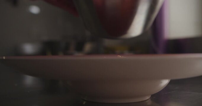 Beautiful slow motion, sideways shot of a dish while serving "octopus casserole" with a spoon inside a restaurant kitchen.