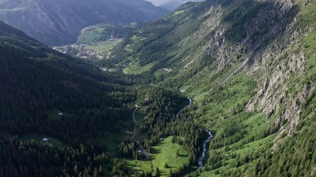 Cascate del rutor waterfall in a lush, green valley with mountains, aerial view