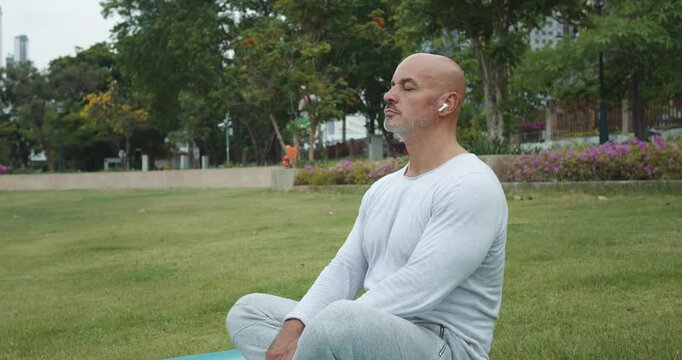 Man in park on mat takes lotus pose for meditation Correct pose is key to comfort and effectiveness practice. By focusing on pose and breathing meditator lets go of thoughts and enters state of peace.