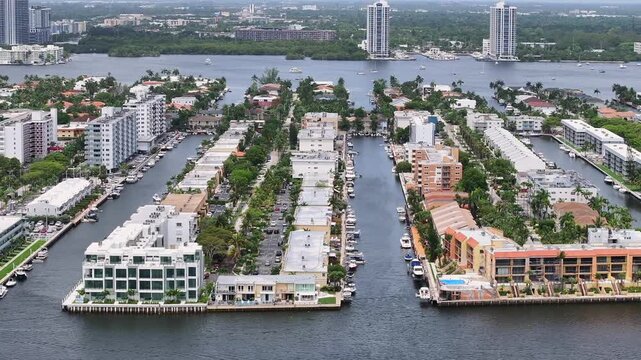 Poinciana Island Condominium in Sunny Isles Beach, Florida. Parking yachts and boats at channel. Aerial lateral wide shot. Arlen House Condominium Association.