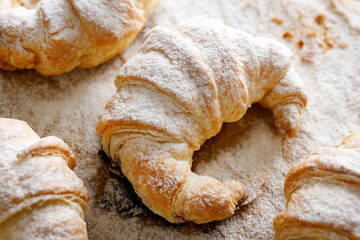 Croissant sprinkled with powdered sugar, close-up. 