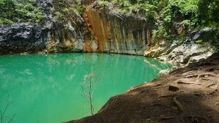 An image of a serene emerald-green lake surrounded by rocky cliffs and dense forest.