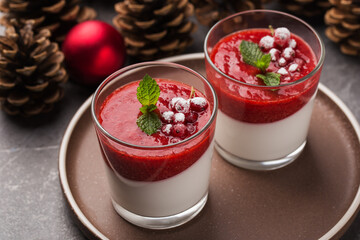 Vegan dairy free coconut Panna cotta with strawberry sauce in glasses on a dark stone table. Healthy dessert. Christmas and New Year's composition with red Christmas balls, pine cones.