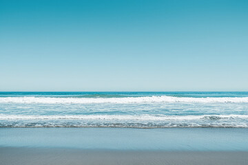Fototapeta premium A tranquil ocean horizon embraces gentle waves that whisper secrets of serenity beneath a vast, clear blue sky, inviting peace and reflection.