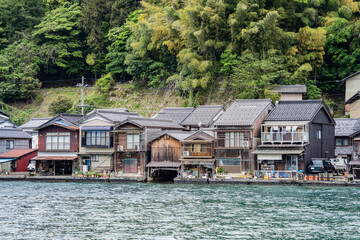 Obraz premium Beautiful scenic view with the wooden traditional waterfront boat houses called funaya around Ine Bay, in the village Ine, Japan