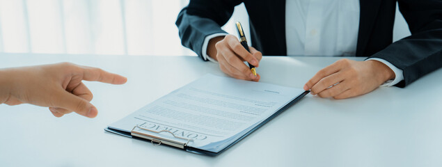 Business executive signing contract agreement document on the bale with the help from company attorney or lawyer service in law firm office. Business investing and finalizing legal processing. Shrewd