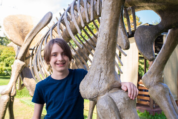 a boy next to a toy dinosaur skeleton in park