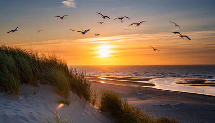 Sunset on the North Sea. View through the dune on the beach. With a lighthouse in the back.