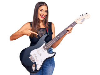 Fototapeta premium Young hispanic woman playing electric guitar smiling happy pointing with hand and finger