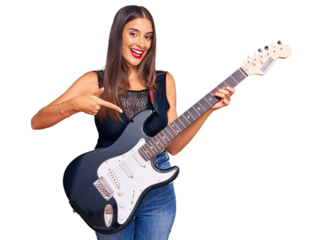 Young hispanic woman playing electric guitar smiling happy pointing with hand and finger