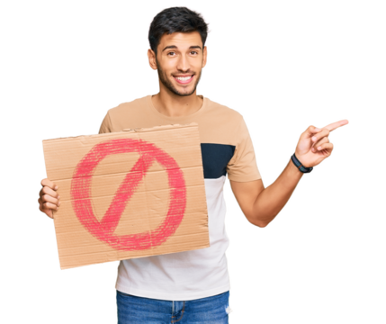 Young handsome man holding prohibited warning banner smiling happy pointing with hand and finger to the side