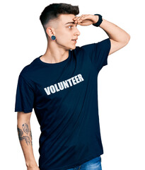 Young caucasian boy with ears dilation wearing volunteer t shirt very happy and smiling looking far...