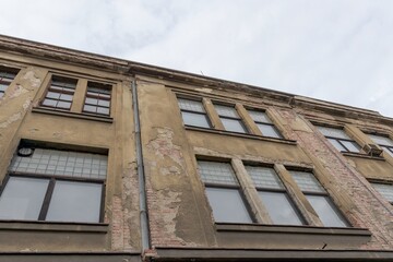 Obraz premium Historic old classic classical german19th 20th century ruined derelict abandoned textile manufacturing industrial factory building brickwork cracked concrete facade scene with broken wooden roof 