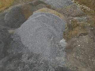 Large high Gray Paving gravel heap pile mound of building pavement construction material small stones pebble of quartz