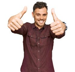 Young hispanic man wearing casual clothes approving doing positive gesture with hand, thumbs up...