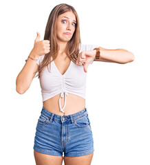 Young beautiful blonde woman wearing casual white tshirt doing thumbs up and down, disagreement and agreement expression. crazy conflict