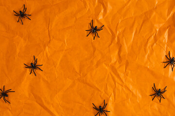 Halloween background. Flat lay. Top view of Halloween decorations with spiders on orange paper background. Halloween concept