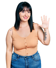 Young hispanic plus size woman wearing casual clothes showing and pointing up with fingers number five while smiling confident and happy.