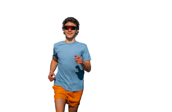 Young man jogging against transparent background, wearing a blue t-shirt, orange shorts, and futuristic sunglasses. Vibrant, healthy lifestyle concept