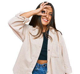 Beautiful hispanic woman wearing casual clothes smiling happy doing ok sign with hand on eye looking through fingers