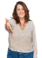 Young plus size woman wearing casual clothes smiling friendly offering handshake as greeting and welcoming. successful business.