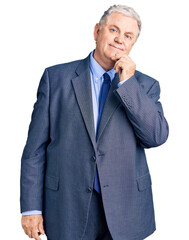 Senior grey-haired man wearing business jacket looking confident at the camera smiling with crossed...
