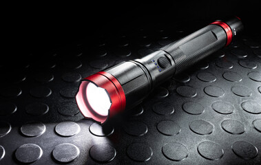 All metal flashlight illuminated on a rubber mat