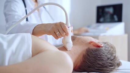 Doctor woman performing neck ultrasound exam on male patient. Medicine service concept. Thyroid...